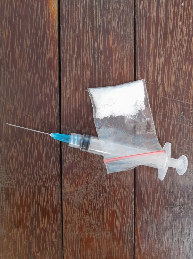 An illustration depicting crystal meth or cocaine-type narcotics alongside syringes.






