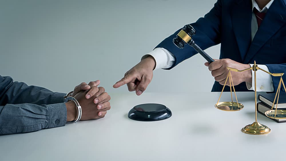 Locked Man Hands and scales of justice with a lawyer holding a hammer pointing to the hand